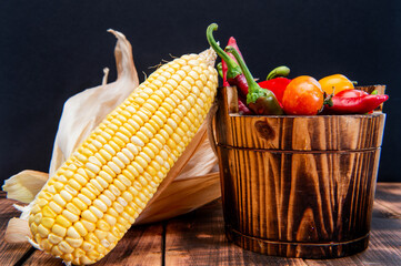 Fresh corncob with peppers and tomatoes organic vegetables natural food in wooden bucket, mexican