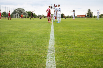 Football center line, footballers during the match in the background - obrazy, fototapety, plakaty