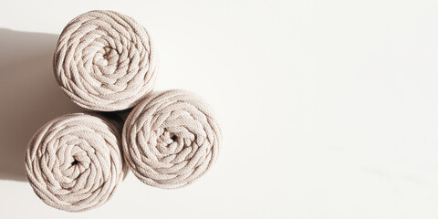 Fototapeta na wymiar Handmade macrame braiding and cotton threads on white background. Hobby knitting cotton yarn reel. Natural cotton cord. Female hobby. Copy space. Banner