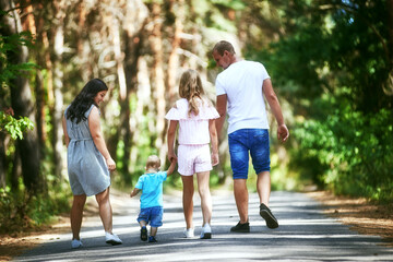 Family with two children walking in summer park together