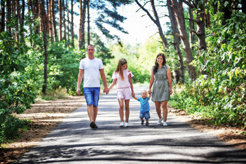 Family with two children walking in summer park together