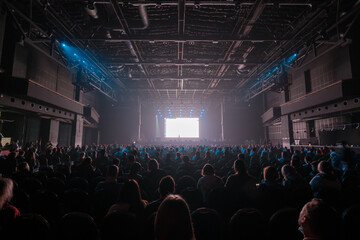 Audience sitting in front of stage with screen