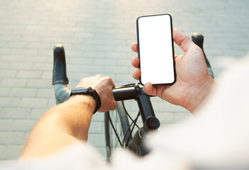 The cyclist is holding the mobile phone with blank white screen in one hand and bicycle in another...