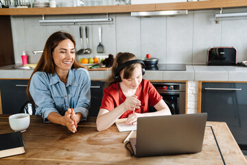 White woman helping her daughter with down syndrome during online lesson