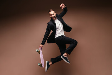 Guy in stylish suit jumps on skateboard on isolated background