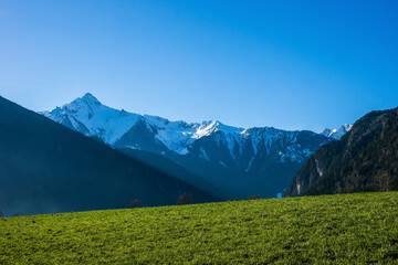 Fototapeta na wymiar Spring view of the green field against the snow covered Mt. Ahorn. Mayrhofen ski resort, Tyrolean Alps, Austria.