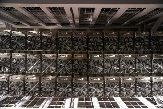 Bitcoin ASIC miners in warehouse. ASIC mining equipment on stand racks for mining cryptocurrency in steel container. Blockchain techology application specific integrated circuit units storage.