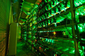 Bitcoin miners in large farm. ASIC mining equipment on stand racks mine cryptocurrency in steel...