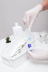 Vertical close up of manicurist  using syringe and liquid sanitizer to prepare disinfectant