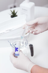 Vertical close up of hands of manicurist preparing disinfecting solution for manicure instruments