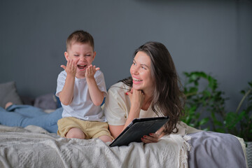 mother and son with tablet at home. Mother showing media content on line to her son in a tablet in the living room in a house interior