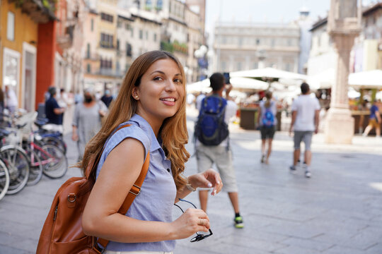 Fototapeta Dynamic attractive traveler girl visits Italy with friends. Beautiful young tourist woman doing a quick tour of Europe in company.