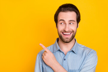 Photo portrait of young man smiling pointing blank space advising positive isolated on vivid yellow...