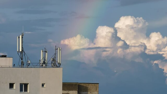 Timelapse of rainbow, Cumulus congestus clouds and telecommunication antennas. Broadcast, 3G, 4G, 5G, mobile network, technology.