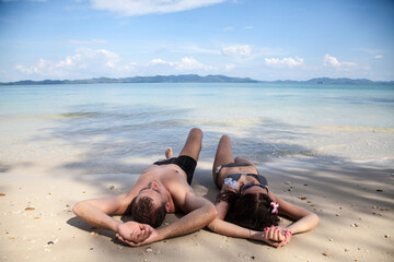 A happy couple in love is lying on the sand on the seashore. Rest, Relaxation, holidays. A man and a woman together on the ocean Coast. The honeymoon, the newlyweds are resting.