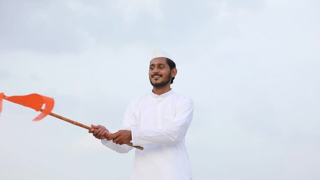 Young indian man (pilgrim) in traditional wear and waving religious flag.