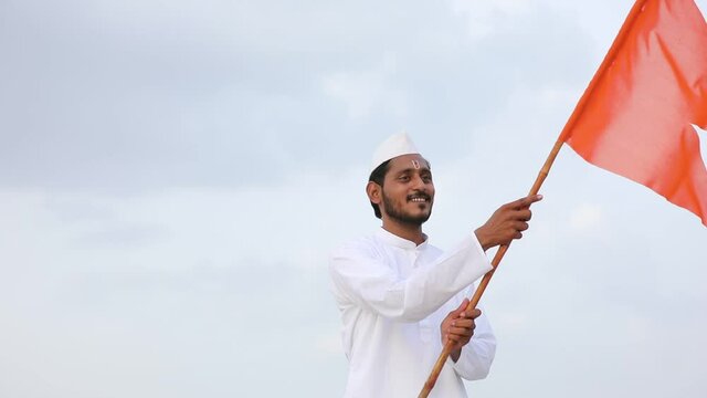 Young indian man (pilgrim) in traditional wear and waving religious flag.
