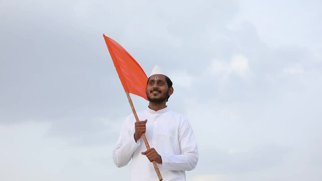 Young indian man (pilgrim) in traditional wear and waving religious flag.