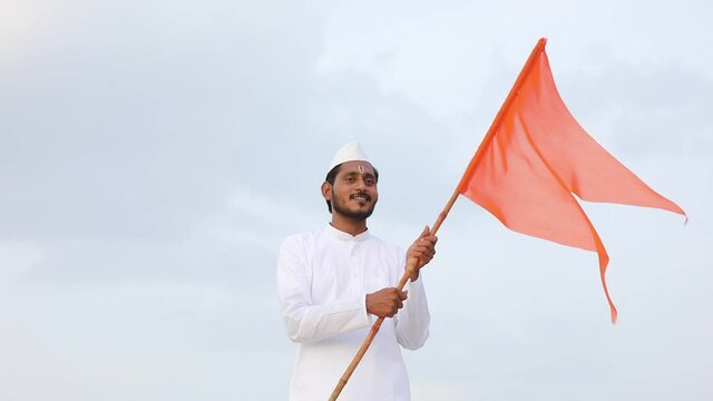 Young indian man (pilgrim) in traditional wear and waving religious flag.
