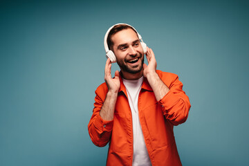 Man in orange jacket and white t-shirt listening to music in headphones