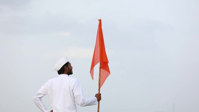 Young indian man (pilgrim) in traditional wear and waving religious flag.