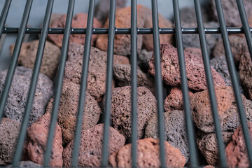 Fragment of a barbecue grill and lava stones. Selective focus. Space for lettering and design