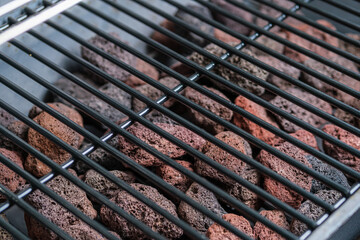 Fragment of a barbecue grill and lava stones. Selective focus. Space for lettering and design