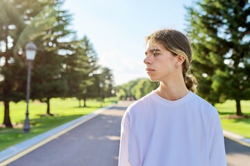 Portrait of handsome teenage guy, profile view outdoors, copy space