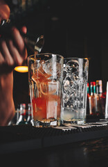 bartender hand mixing cocktail Lemonade with ice cubes in glass to customers at bar