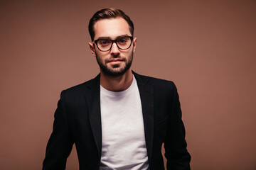 Man in suit and glasses looks into camera on brown background