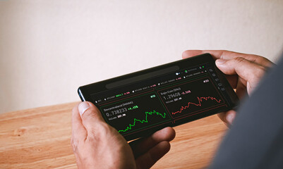 hand holding smartphone with stock graph of cryptocurrency interface, trading concept, business...