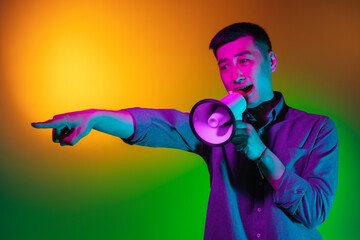 Portrait of Asian young man isolated on studio background in gradient green yellow neon light, colour filter. Concept of human emotions, facial expression.