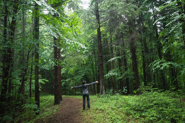 Girl walking in a green forest in the rain
