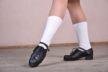 Close-up of female legs in black leather shoes dancing national Irish dances.
