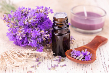 A bottle with lavender oil and delicate lavender flowers on a white background.