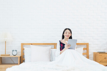 Fototapeta na wymiar Asian woman using tablet in bed. Asian women are using the tablet on the bed in the morning.