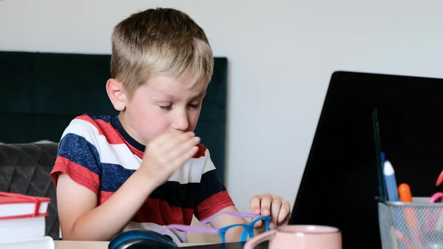 Little boy taking off glasses massaging dry irritable eyes. Tired child feeling eye strain after using computer. eyestrain concept.
