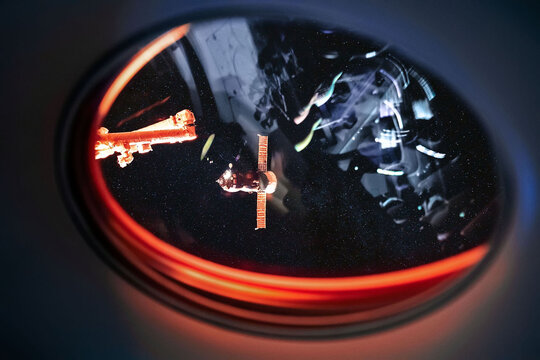 View on ISS Progress resupply ship, View out from a passenger window on the SpaceX Crew Dragon. Docking maneuver near the Space Station. Elements of image furnished by NASA