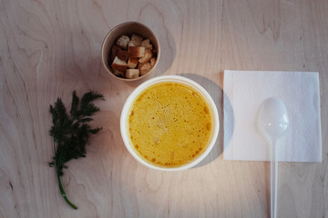 Close-up of mushroom soup in a paper glass. Takeaway food in the restaurant. The concept of vegetarian fast food in the meal industry. Pieces of crackers float in the broth.