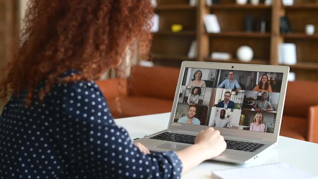 Virtual meeting with group of diverse people, young curly woman glad to meet coworkers online on the distance, laptop screen with many multiracial colleagues involved video conference