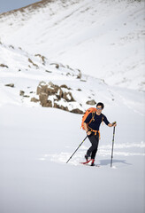 Fototapeta na wymiar Winter sports - young man walking with snowshoes in high mountains covered with lots of snow (selective focus on the mountain in the background)