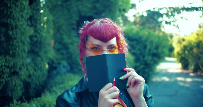 orange glasses Girl flirting with the eyes and covering her face with a note book