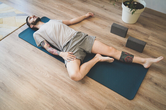 Young man lying on yoga mat relaxing and deep breathing. Meditating on sports mat
