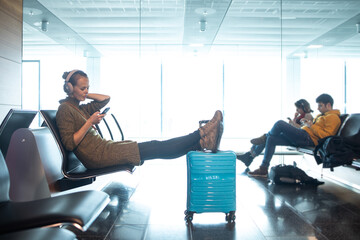 A female traveller waiting for her flight boarding time at the gate of a modern airport in the...