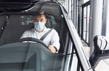 Young man in white shirt is sitting inside of a modern new automobile