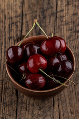 dark red cherry at bowl on a rustic table top. above view