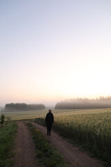 silhouette of a man walking in a scenic countryside landscape at sunrise