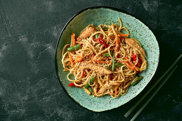 Buckwheat udon wok noodles with chicken, vegetables cilantro sauce in a green plate. Close up, selective focus