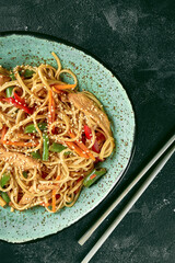 Buckwheat udon wok noodles with chicken, vegetables cilantro sauce in a green plate. Close up,...