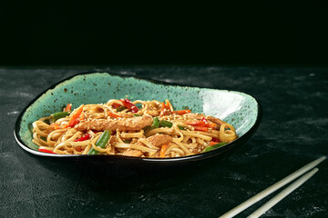Buckwheat udon wok noodles with chicken, vegetables cilantro sauce in a green plate. Close up,...